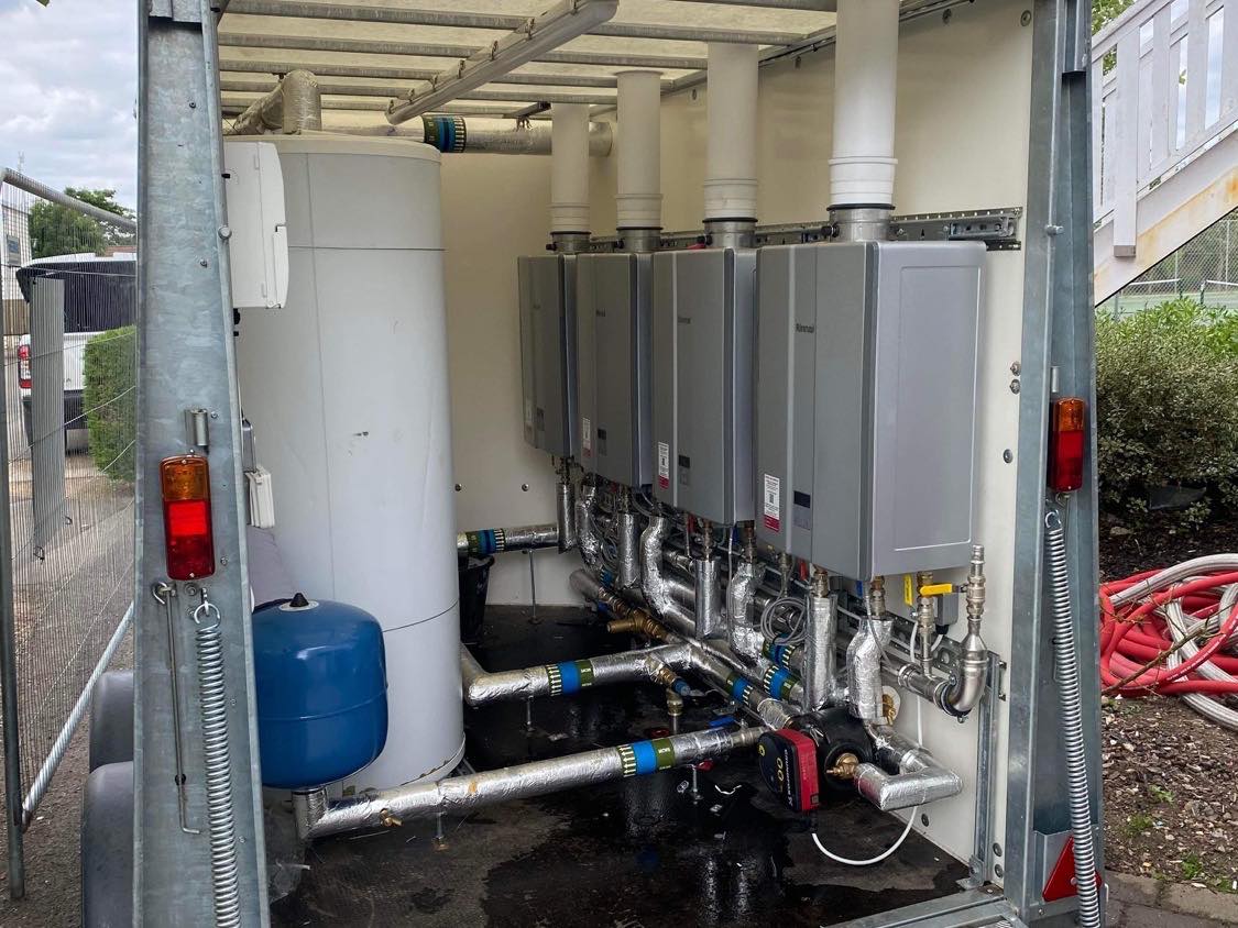 A trailer-mounted hot water unit with four continuous flow water heaters and a storage cylinder